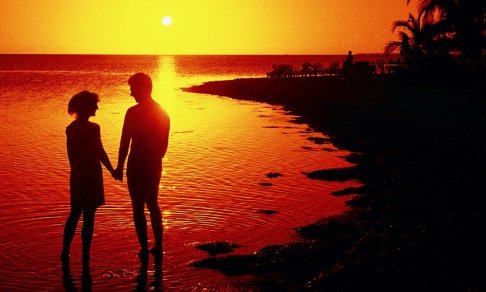 Silhouette of a man and woman holding hands on a beach at sunset Silhouette of a man and woman holding hands on a beach at sunset