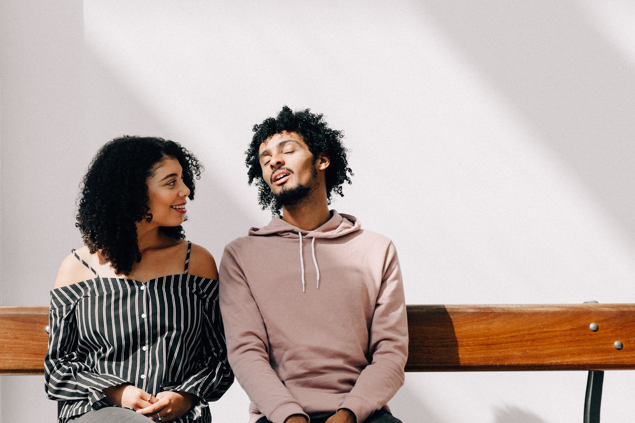 Young couple sitting on a bench singing and laughing