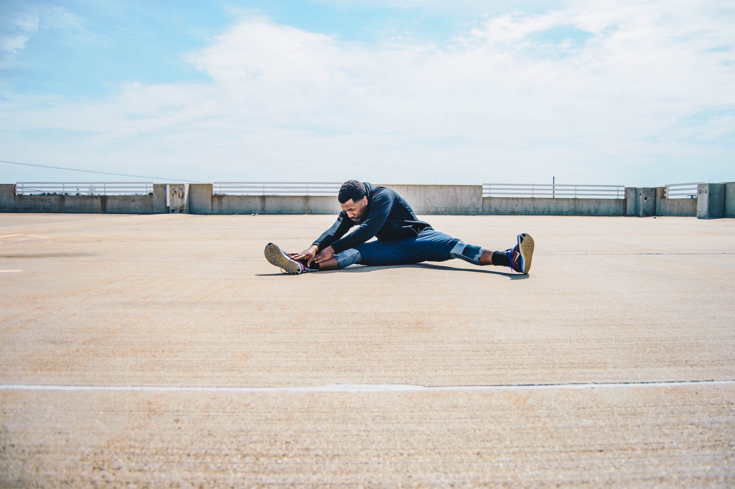 African American man in leggings and shorts stretching before a workout.