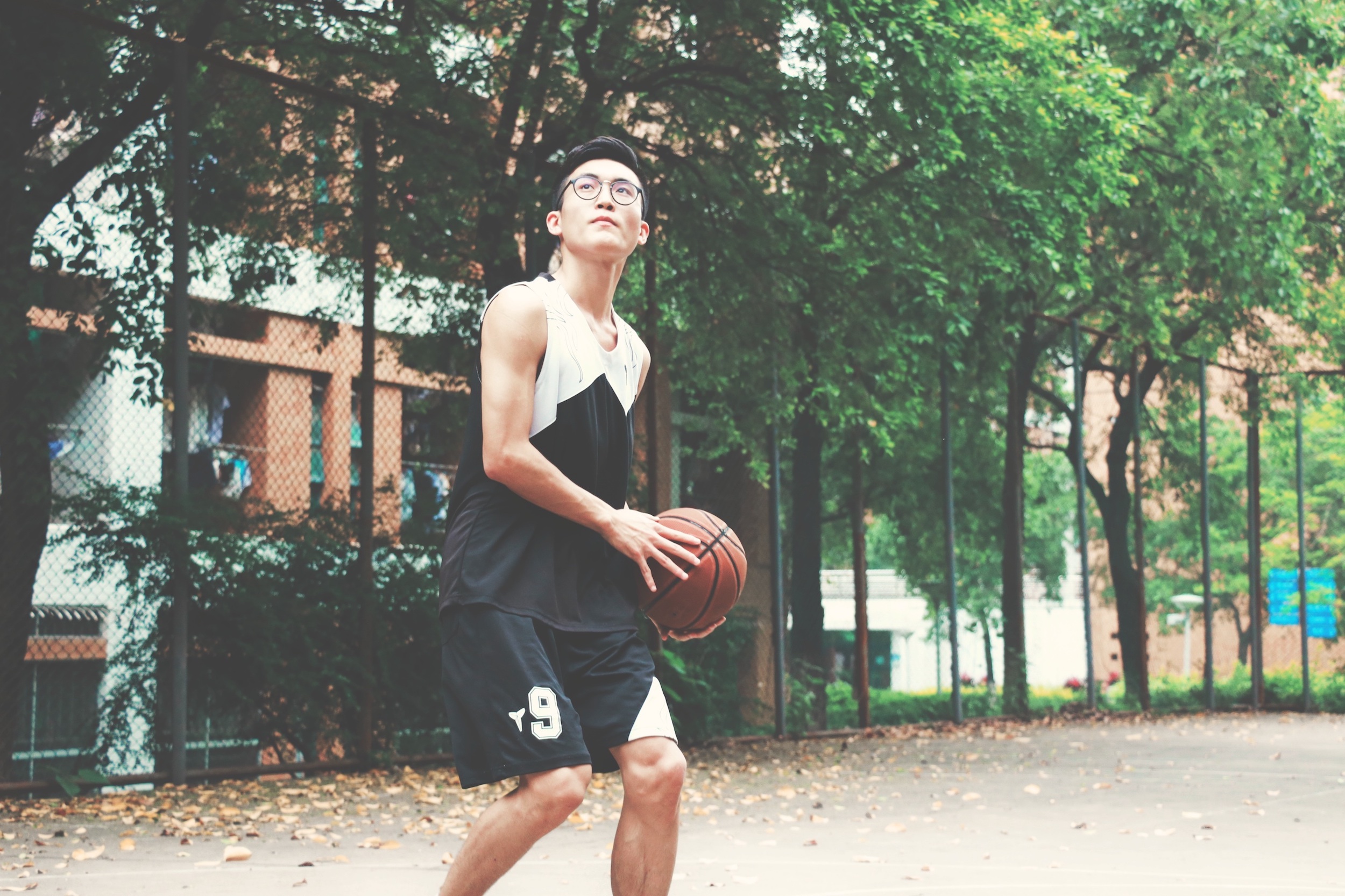 Young Asian male playing basketball.