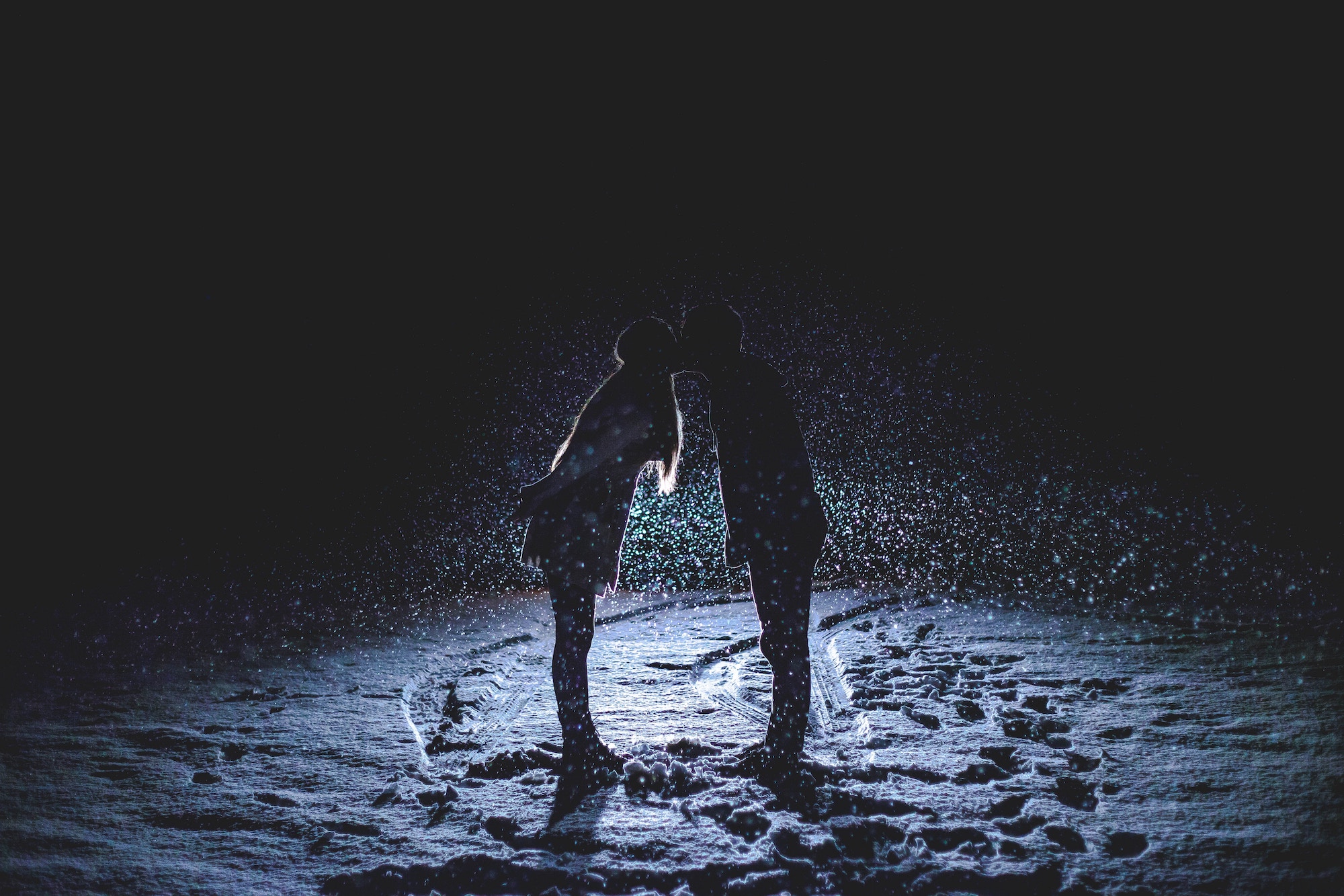 Two lovers kissing on a dark beach.