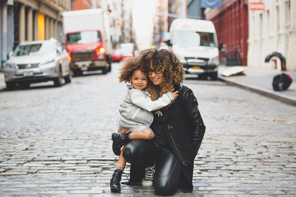 The same mother and daughter hugging in the middle of a brick street.