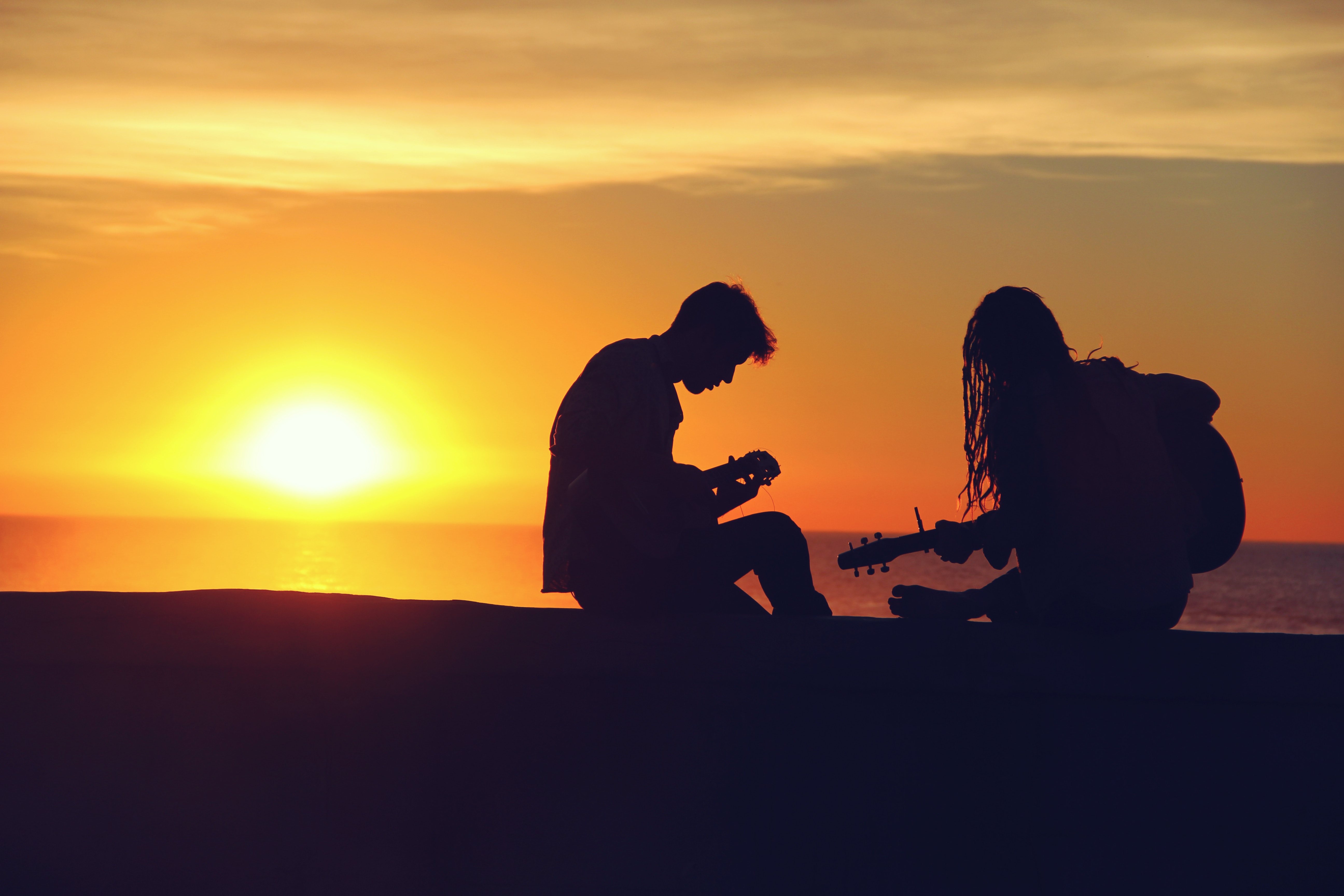 Young couple playing guitar in sunset