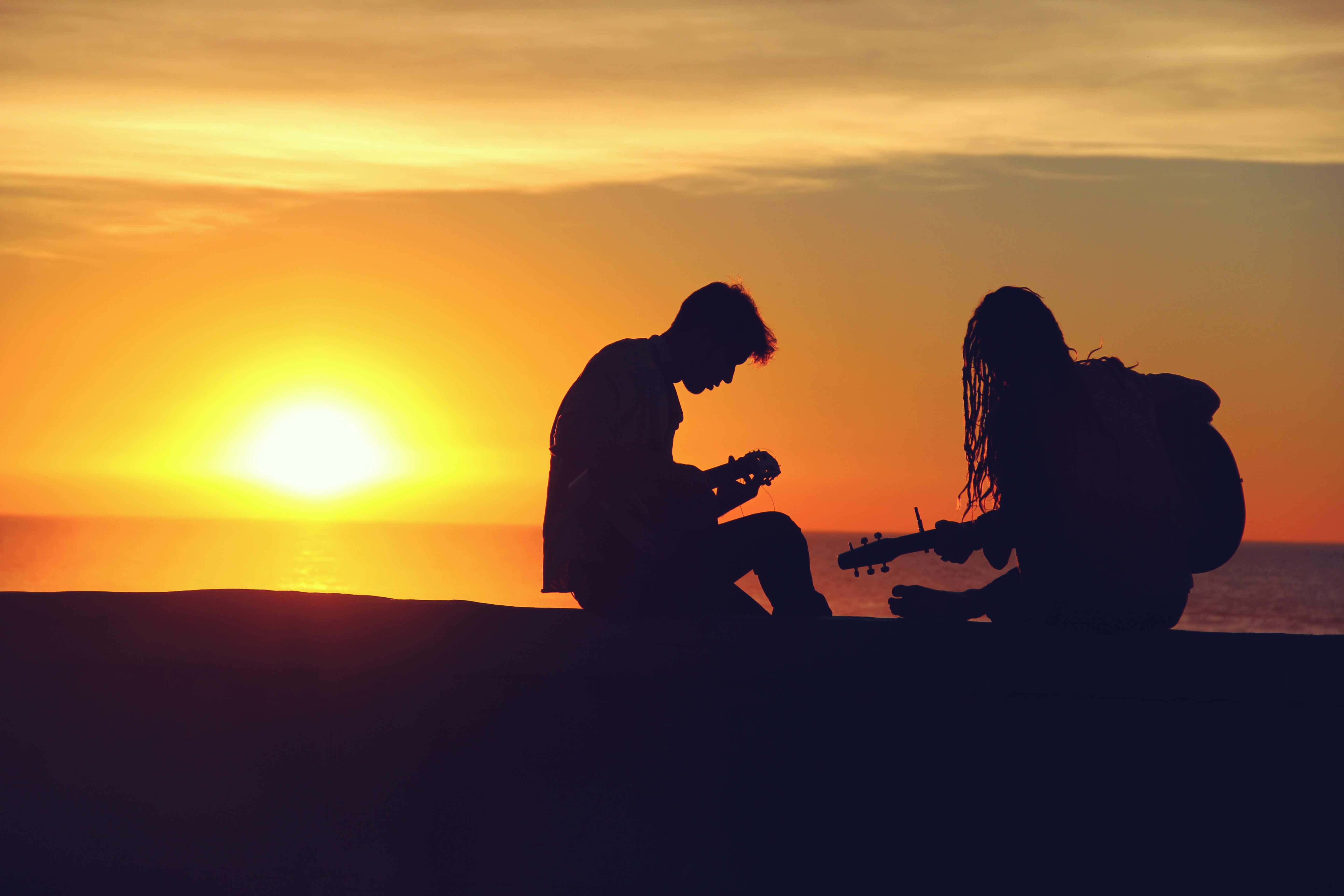 A couple playing music on beach in sunset