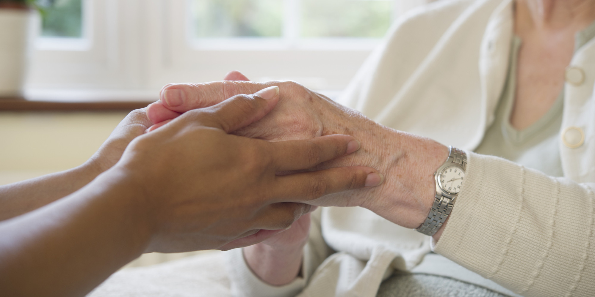 Young caregiver embracing the hands of an elderly woman
