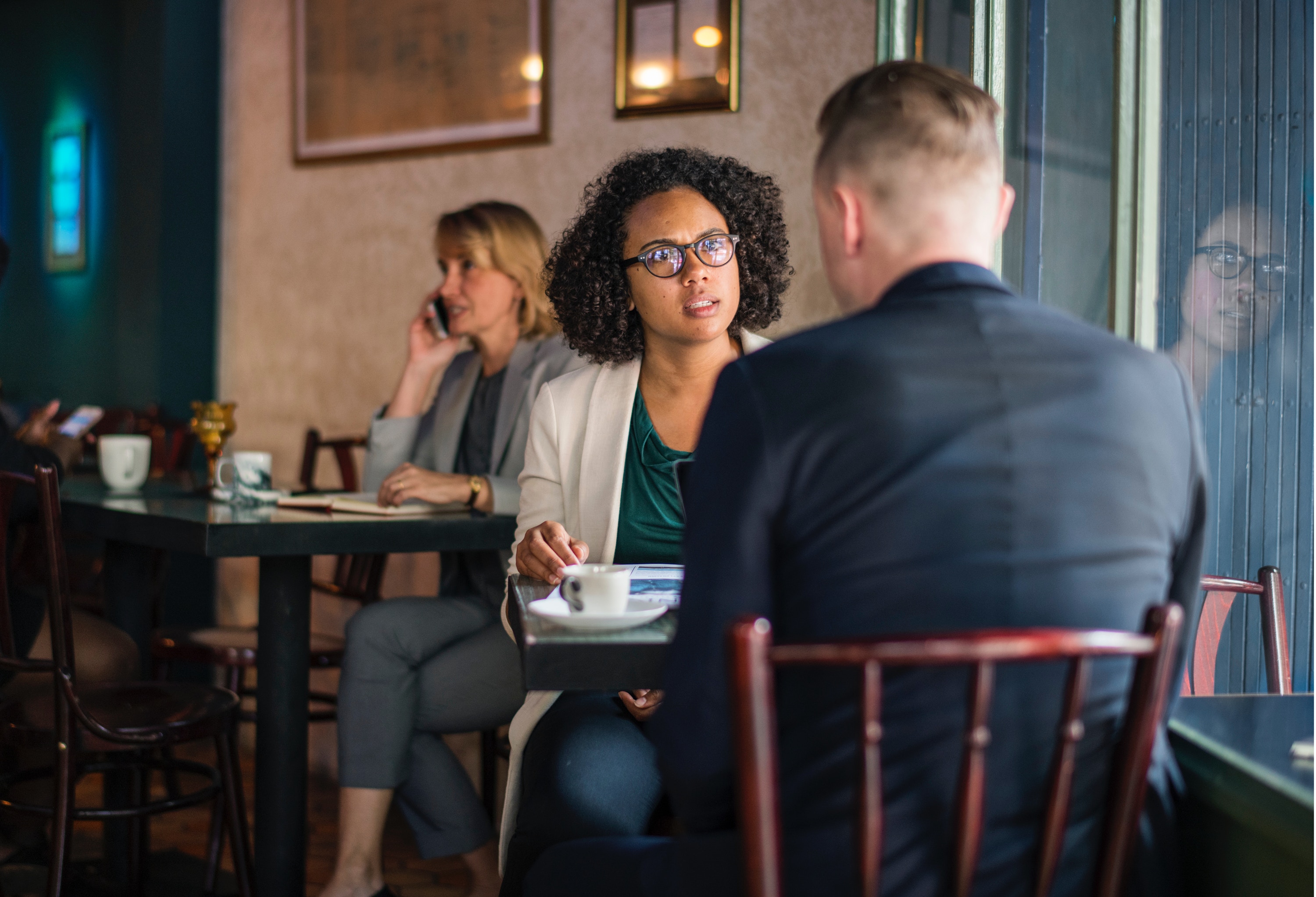 Man and woman with concerned look on her face sitting at a table by the window in a coffee shop conversing.