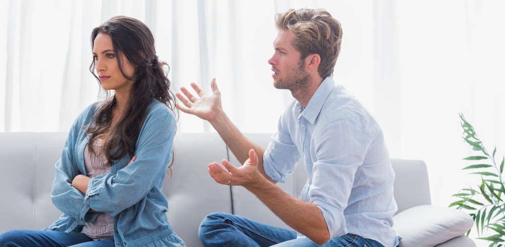 Woman with her arms crossed and back to her significant other, who is unsuccessfully trying to converse with her.