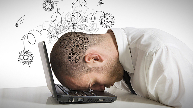 Man in a white collared shirt with his head on a laptop keyboard