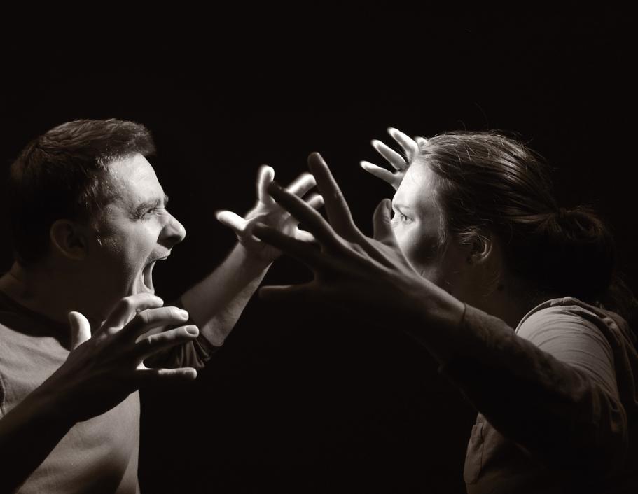 Black and white photo depicting an angry couple yelling with their hands raised