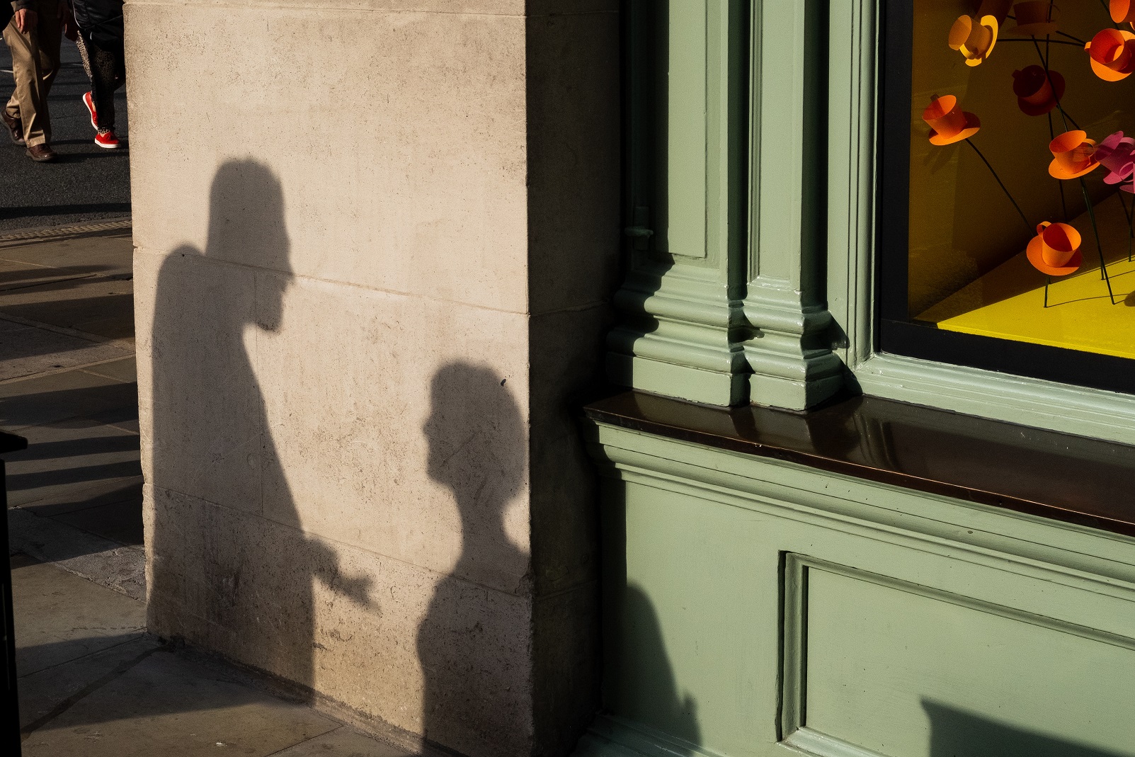 Shadow on side of building of man and woman having an unpleasant conversation.