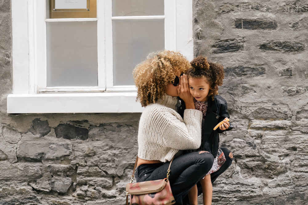 African American mother whispering to her daughter