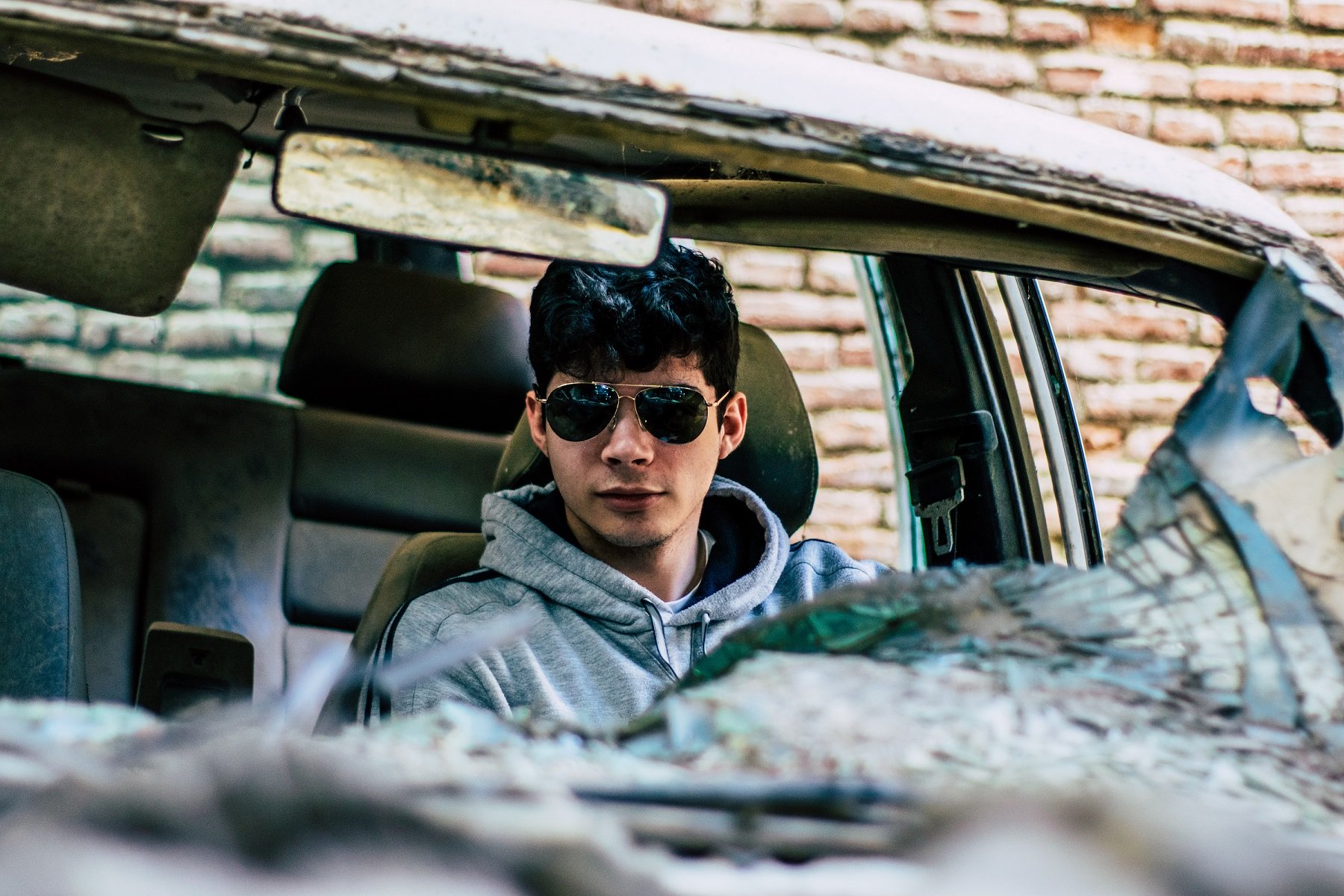 Boy in car with a smashed windshield and ruined interior fabric