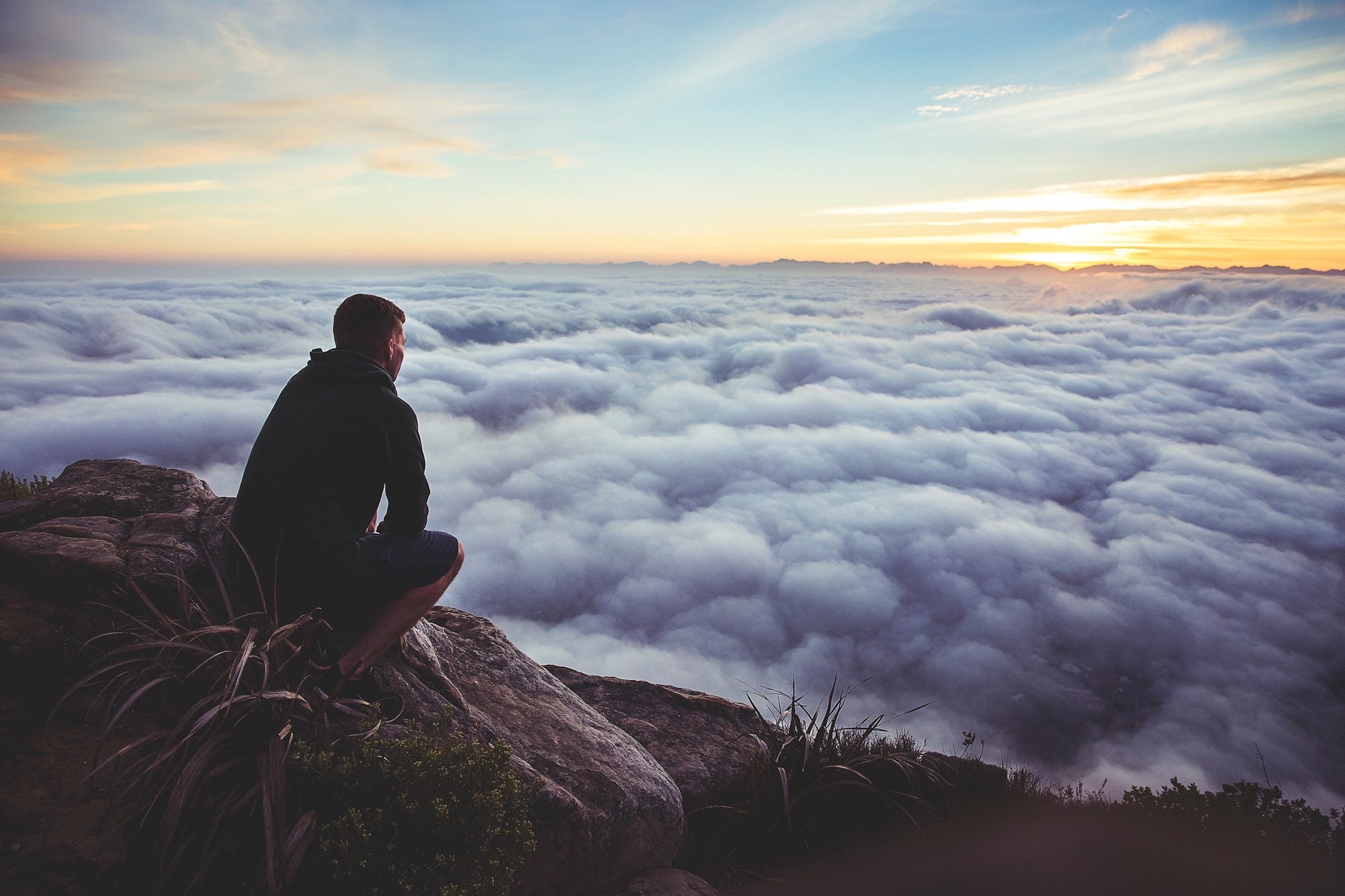 A man looking into the clouds on top of a mountain