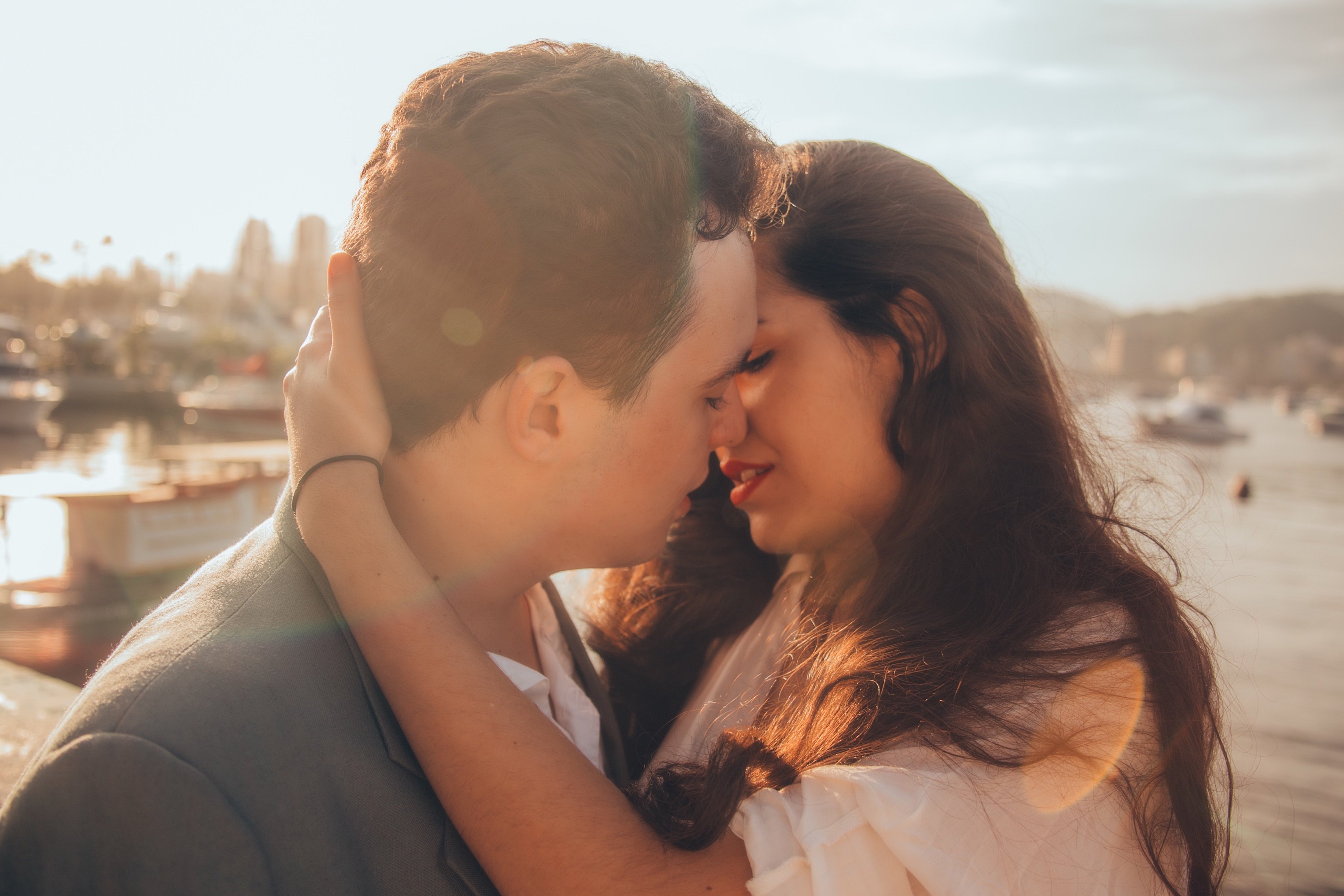 Couple leaning in for a kiss amidst a sunset