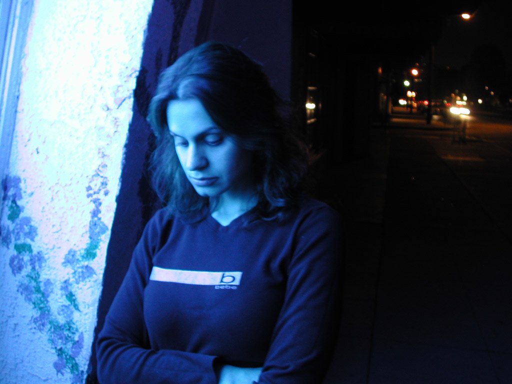 Woman in blue standing by a window and looking down with her arms crossed