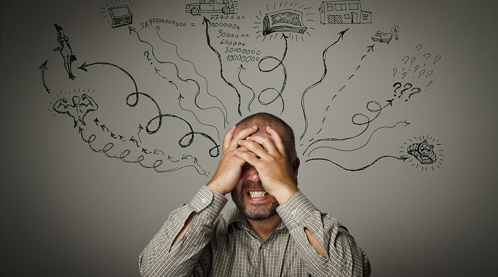 Man covering his face with his hands with scribbles drawn outward from his head.